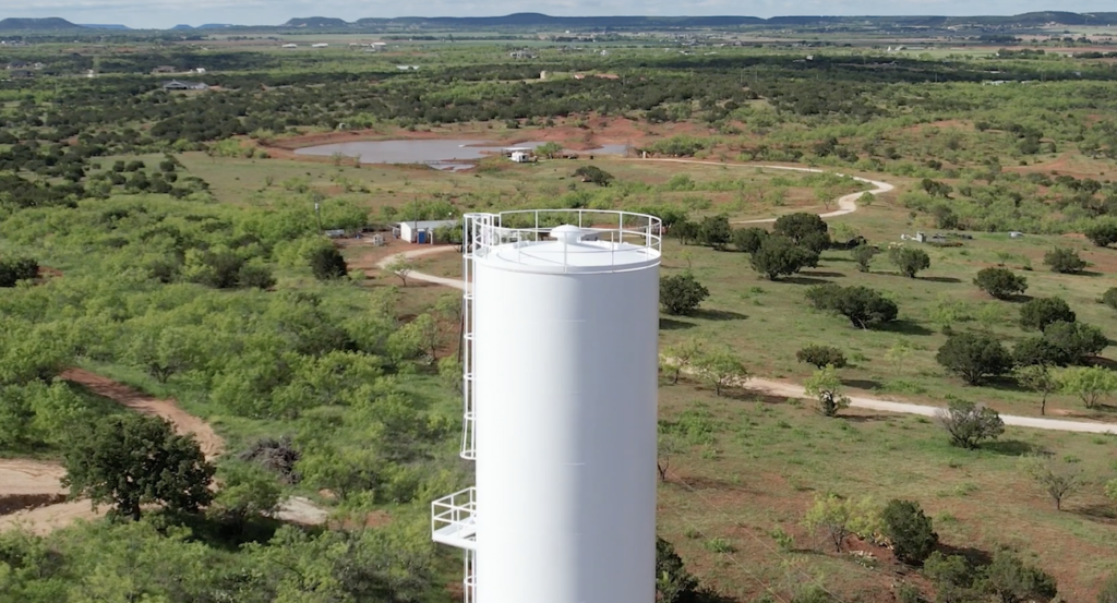 Round Rock water tower aerial view of white water supply tank surrounded by trees and greenery in Round Rock, TX