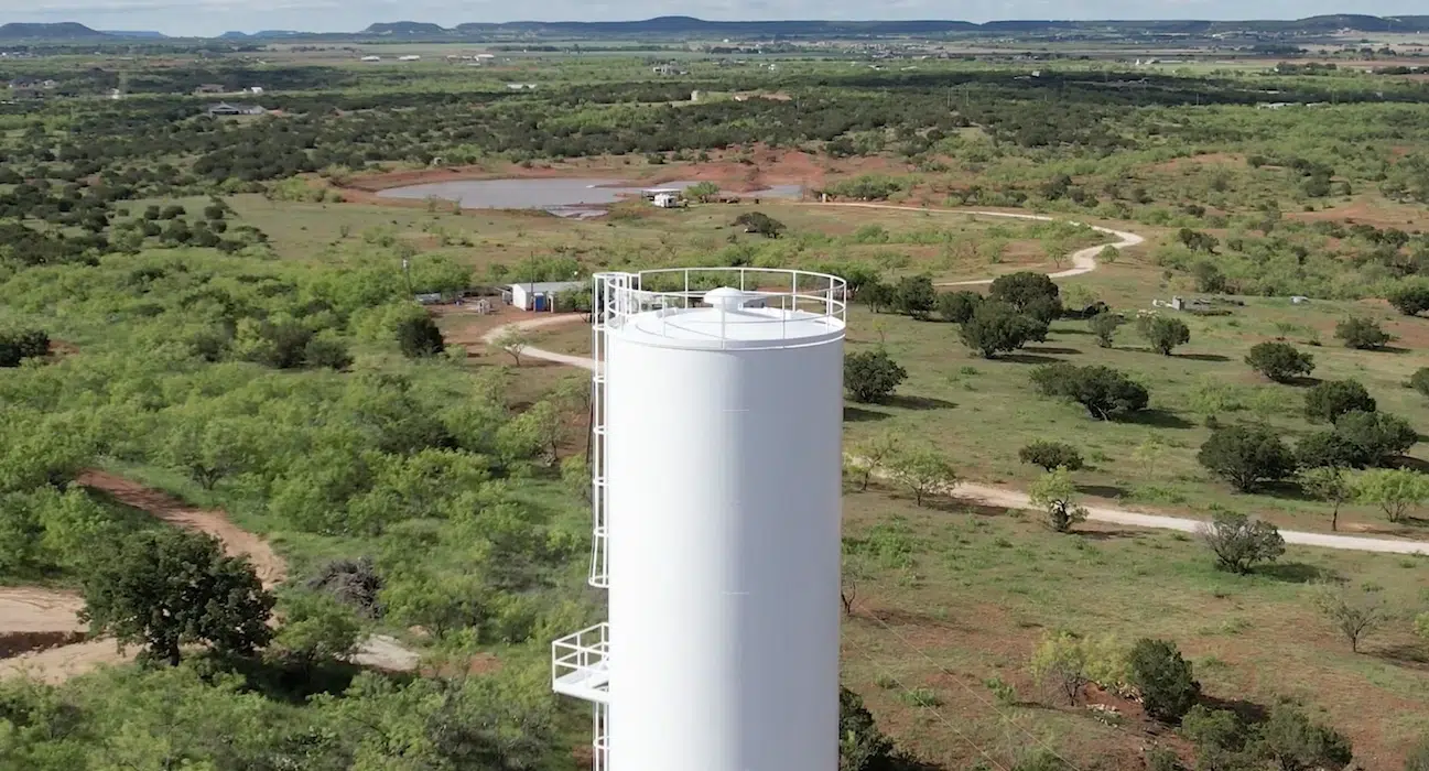 aerial view of white water supply tank surrounded by trees and greenery