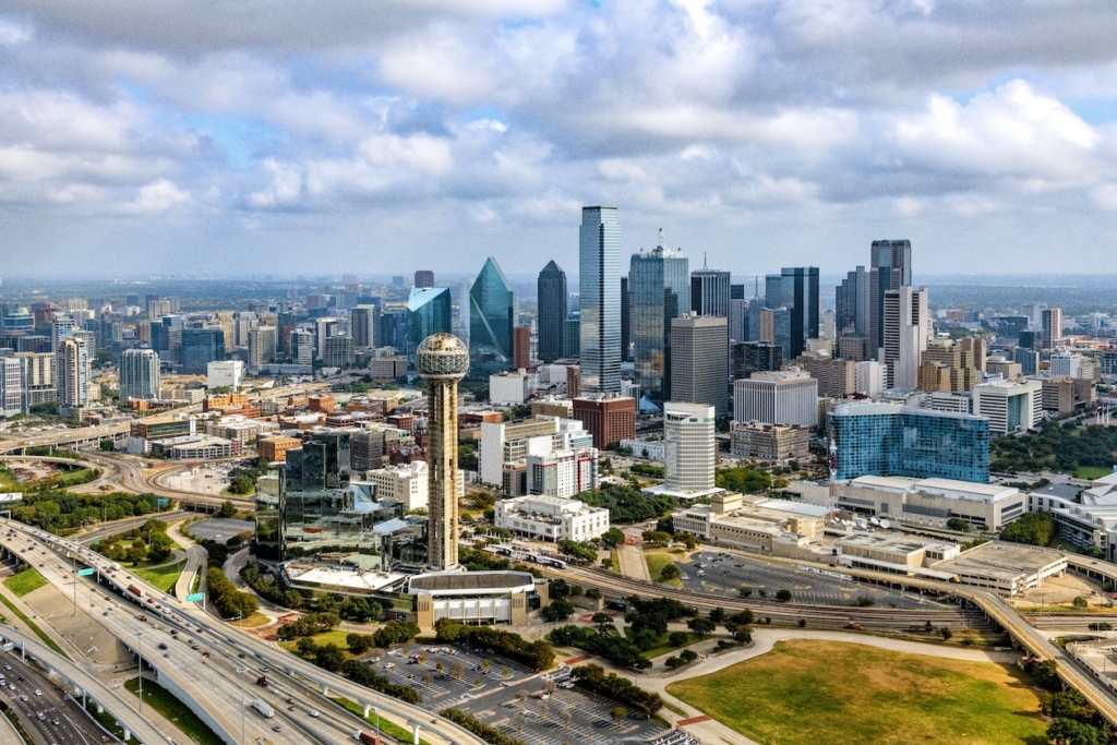 twf-faq-more-people-moving-dallas Aerial view of buildings and highways in downtown Dallas, TX