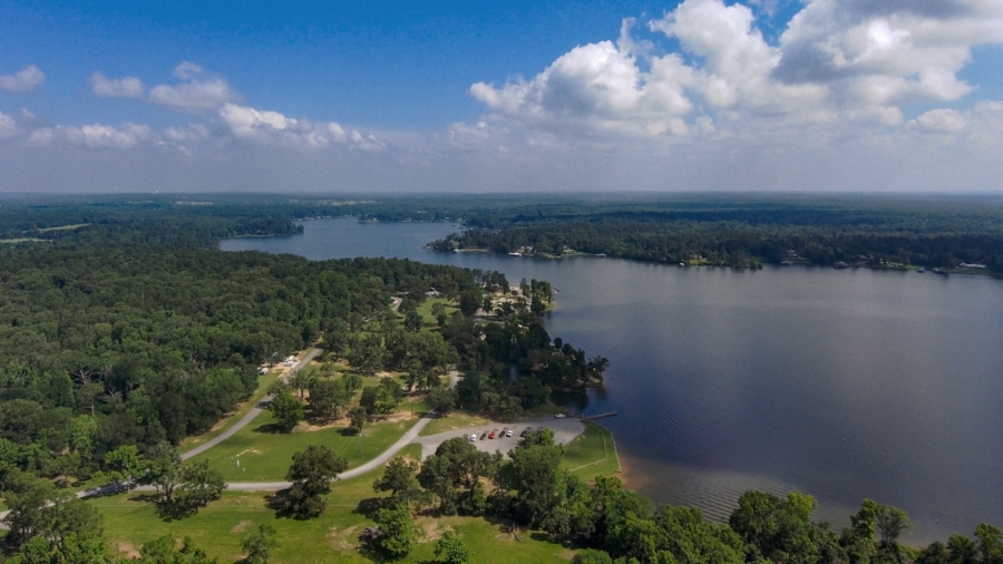 Scenic aerial view of Lake Tyler surrounded by green forests and blue sky with clouds