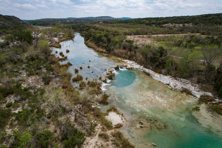 Scenic aerial view of a winding river through a lush green landscape under a cloudy sky.