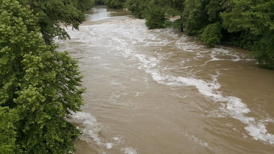 Flooded Guadalupe River with rapid water currents surrounded by green trees