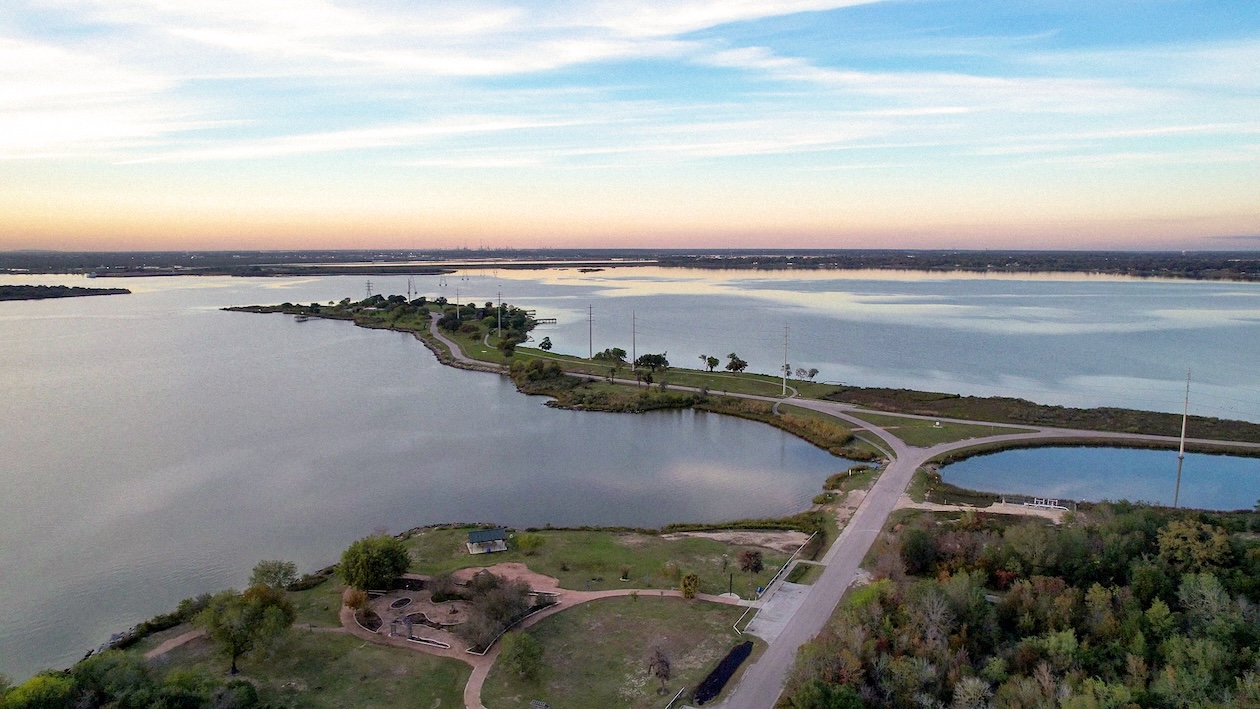 Scenic aerial view of a peninsula surrounded by a calm lake under a colorful sunset sky